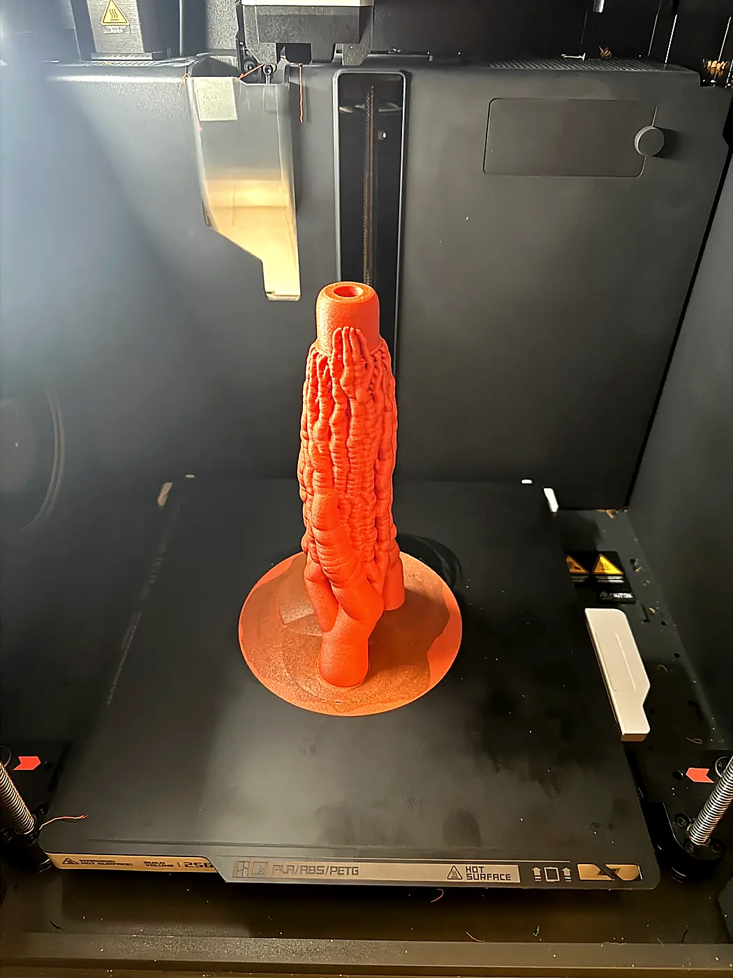 Orange Hamdo body standing on a 3D printer build plate