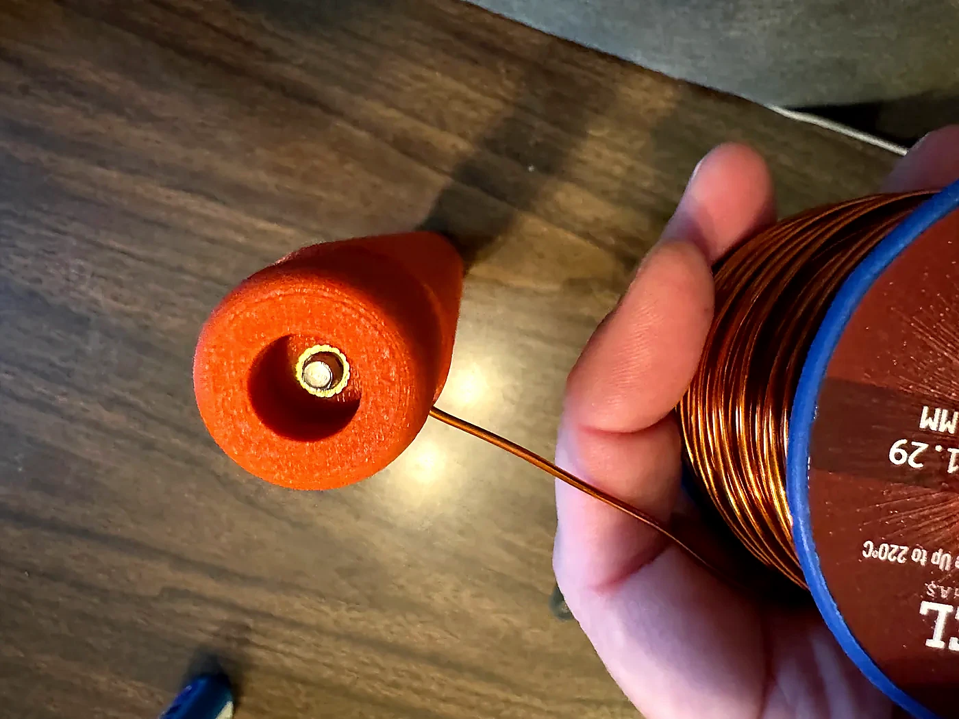 Magnet wire being fed into the upper hole of the Hamdo coil form